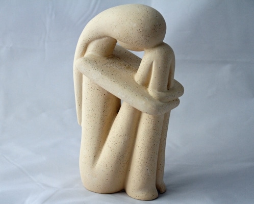 statuette de femme triste qui est recroquevillée sur elle-même, avec la tête dans les genoux